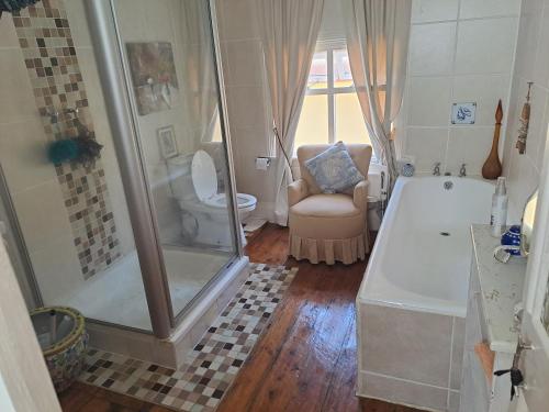 a bathroom with a shower and a chair and a tub at Taste Of Heaven in Bredasdorp