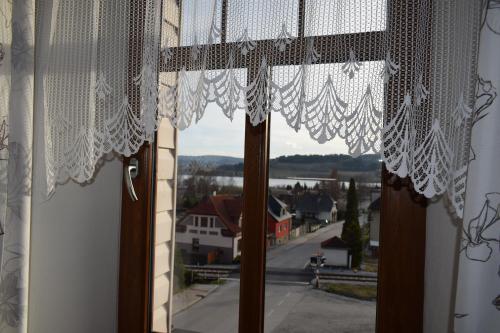 a window with white curtains and a view of a town at Penzion Šumava - APARTMÁN in Horní Planá