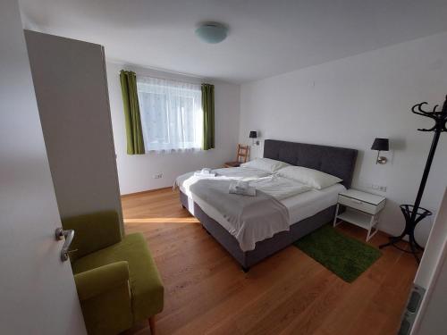 a bedroom with a large bed and a green chair at Appartement Lengdorfer in Untertauern