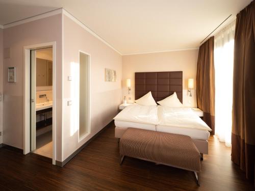 ビーティッヒハイム・ビッシンゲンにあるHotel Eberhards am Wasserのベッドとバスルーム付きのホテルルームです。