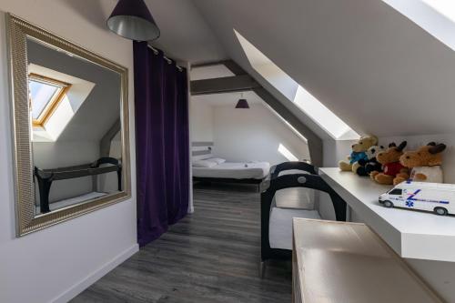 Cette chambre mansardée comprend un miroir et un lit. dans l'établissement Appartement des Grands Champs avec terrasse, à Saint-Aignan