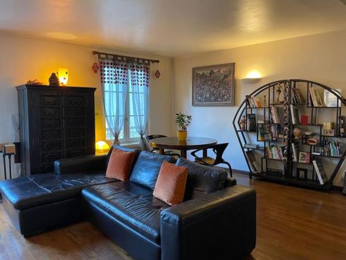 a living room with a black leather couch and a table at Appartement sur le parvis de la cathédrale in Senlis