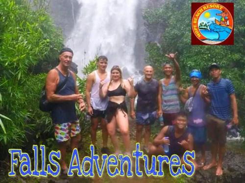 a group of people standing in front of a waterfall at Mope Beach Resort in San Narciso