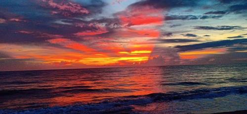 a sunset on the beach with the ocean at Mope Beach Resort in San Narciso