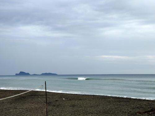 a beach with a wave in the ocean at Mope Beach Resort in San Narciso
