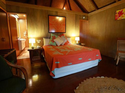 a bedroom with a large bed with a red blanket at Muri Beach Hideaway - Adults Only in Rarotonga