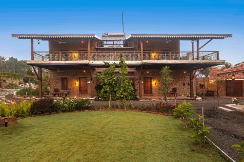 a large house with a large yard in front of it at SaffronStays Lake House Bouganvillea, Nashik - rustic pool villa with great lake views and patio dining in Nashik