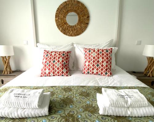 una camera da letto con un letto con due cuscini e uno specchio di Cairnvillas Villa Essencia C45 - Luxury Villa with Private Pool near Beach ad Aljezur