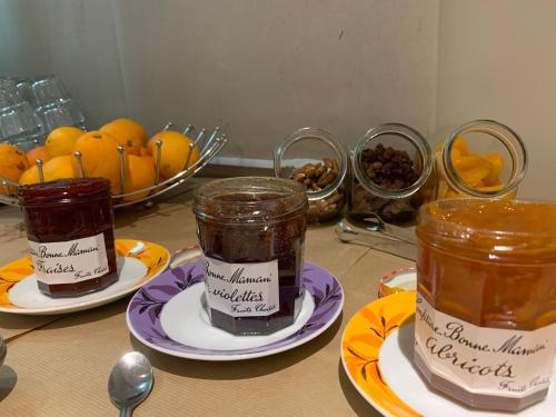 two jars of jam on plates on a table with fruit at Hôtel des Etats-Unis in Toulouse