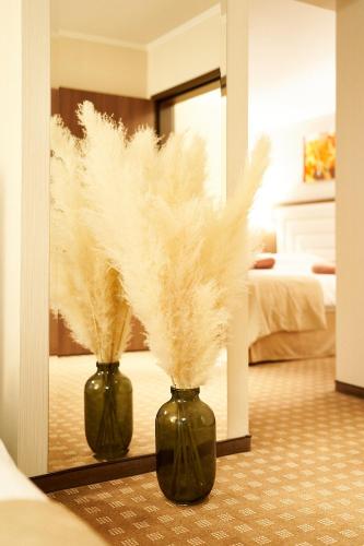 two green vases filled with feathers in a bedroom at Petrodava ONE in Piatra Neamţ