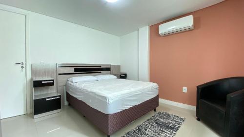 a small bedroom with a bed and a television at Ótimo apartamento na praia de Bombas. in Bombinhas