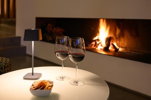 two wine glasses on a table with a fireplace at Inspira Liberdade Boutique Hotel in Lisbon