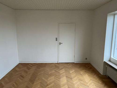 an empty room with a white door and wooden floors at Great view apartments 1 in Aalborg