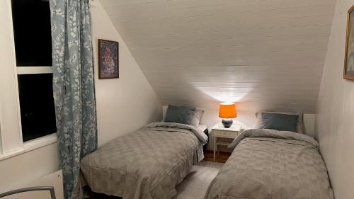 a bedroom with two beds and a lamp on a table at Cozy little house in Tromsø city in Tromsø