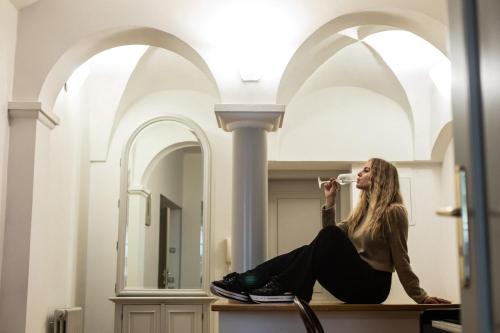 Una donna seduta su un bancone bevendo una tazza di caffè di Residence Thunovska a Praga