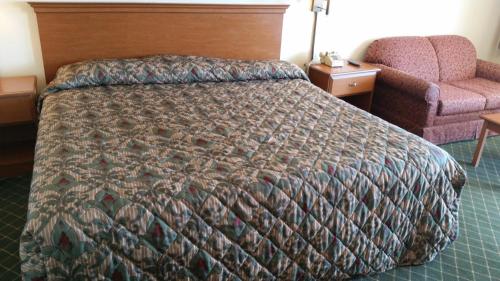 a hotel room with a bed and a chair at Economy Inn Dillon in Dillon