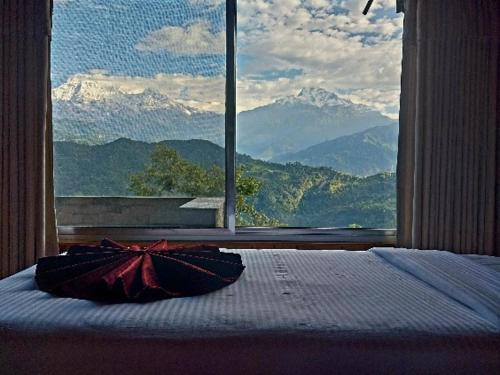 a bedroom with a bed and a large window with mountains at Himalayan Deurali Resort in Pokhara