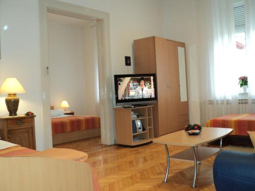 Apartment Horvat في زغرب: غرفة معيشة فيها تلفزيون وغرفة فيها سريرين