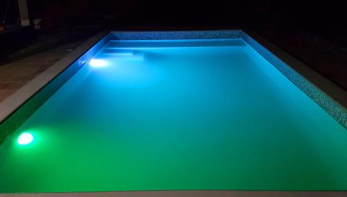 einen Pool mit grüner Beleuchtung in einem Haus in der Unterkunft House Bosnic in Cista Provo