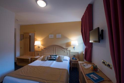 a hotel room with two beds and a television at Hotel La Meridiana in Madesimo