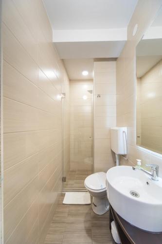 a bathroom with a toilet and a sink and a shower at Garni Hotel President de Luxe in Kragujevac