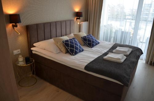 łóżko z niebiesko-białymi poduszkami i oknem w obiekcie Westin House Resort Kołobrzeg Apartament DELUX w Kołobrzegu