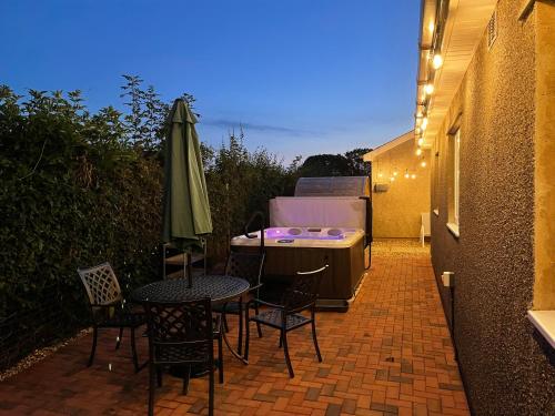 a patio with a table and chairs and a hot tub at Blackthorn Meadow in Pontypool