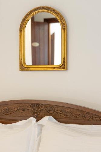 a mirror above a bed with a wooden headboard at Castello di Haria in Kaloú