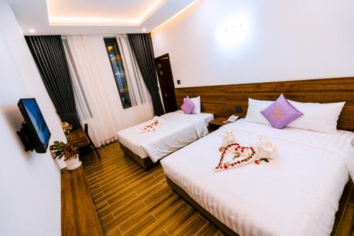 una camera d'albergo con due letti e una televisione di Hue Golden Inn Hotel a Hue