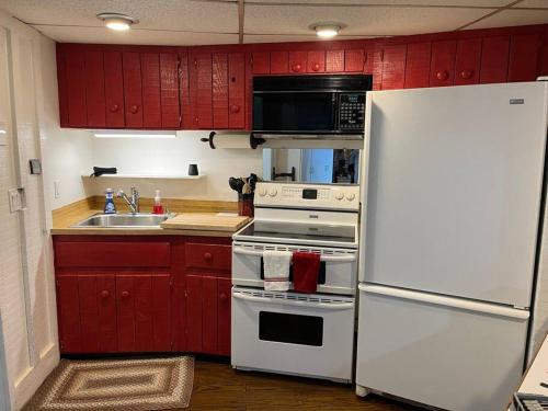 a kitchen with red cabinets and a white refrigerator at 2 Bedroom Apartment overlooks WCU and Cullowhee NC - Smoke and Pet free in Sylva