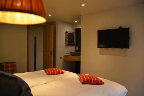 a hotel room with two beds and a flat screen tv at La Légende - Gîte dans un quartier pittoresque in Bouillon