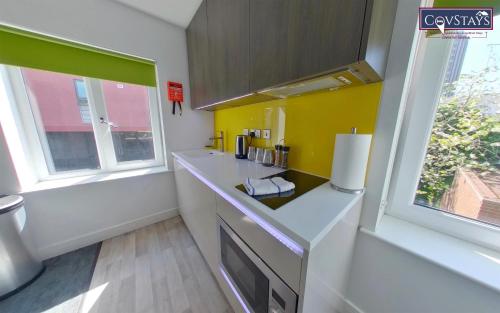 a kitchen with a white counter and a yellow wall at New House - Magnificent Studios in Coventry City Centre, free parking, by COVSTAYS in Coventry