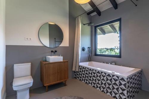 ein Badezimmer mit einer Badewanne, einem Waschbecken und einem Spiegel in der Unterkunft Larraetxea in Isla Becoa