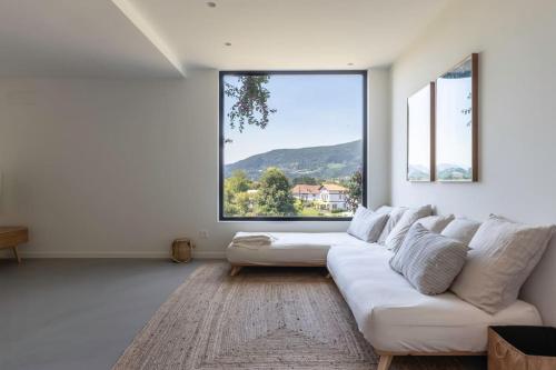 a living room with a white couch and a large window at Larraetxea in Isla Becoa