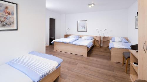 a room with three beds and a desk at Brenzhotel Heidenheim in Heidenheim
