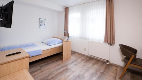 a bedroom with a bed and a desk and a window at Brenzhotel Heidenheim in Heidenheim