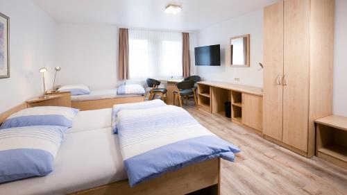 a hotel room with two beds and a desk at Brenzhotel Heidenheim in Heidenheim
