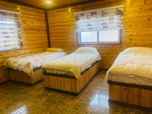 een kamer met 3 bedden in een houten hut bij Green house in Ajloun