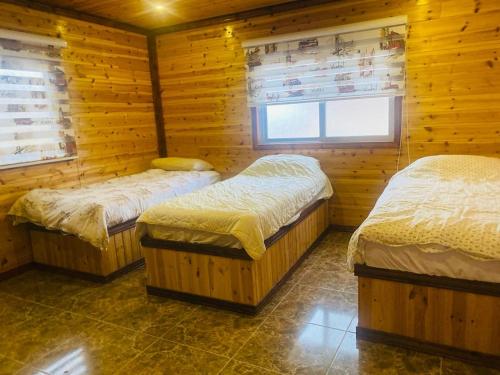 a room with three beds in a wooden cabin at Green houseجوهره الشمال in Ajloun