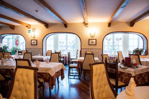 a dining room with tables and chairs and windows at Hotel La Meridiana in Madesimo