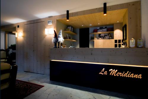 a lobby of a restaurant with a counter with a sign at Hotel La Meridiana in Madesimo