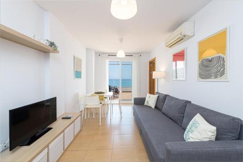a living room with a gray couch and a television at WintowinRentals Amazing Front Sea View & Relax in Torre de Benagalbón