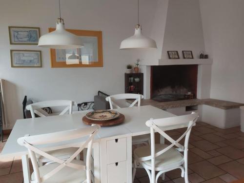 cocina con mesa blanca, sillas y chimenea en Appartamento indipendente, en San Pietro Vernotico