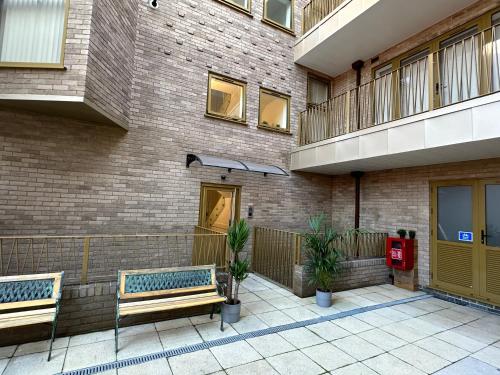 two benches sitting in front of a brick building at LUXURY 2 Bedrooms - 2 BATHROOMS - F5 in London