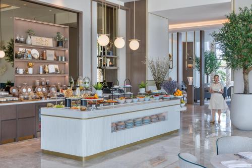 a woman standing in front of a buffet in a restaurant at Address Beach Resort Bahrain in Manama