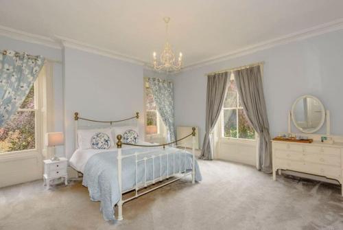 a bedroom with a bed and a dresser and windows at Beech Bank - Georgian luxury near Hadrian’s Wall in Carlisle