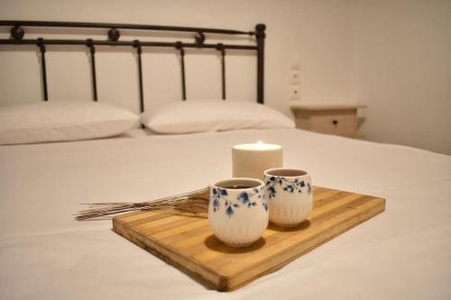 Una vela y dos tazas en una bandeja en una cama en Liberty's House, en Mouresi