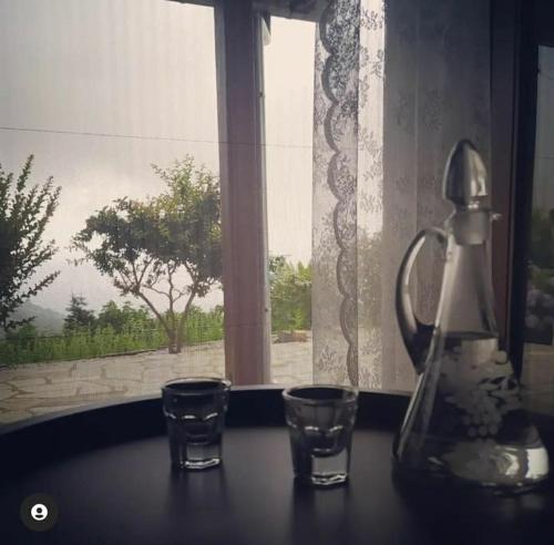un hervidor de agua y 2 vasos sobre una mesa con una ventana en Liberty's House, en Mouresi