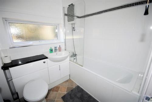 a white bathroom with a toilet and a sink at Perfect couple retreat to unwind&relax with HotTub in Peacehaven