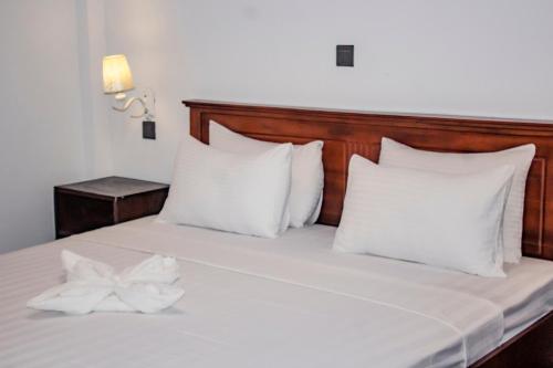 Una cama con almohadas blancas y un arco blanco. en Surf & Party Weligama, en Weligama
